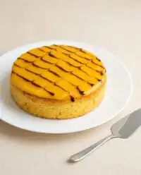 An elegant Mango Fresh Fruit Topped Cake on a marble pedestal showing precise decoration ideas