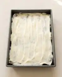 A close up of a zucchini cake with applesauce slice showing the dense, spiced crumb and smooth brown butter cream cheese frosting.