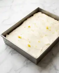 A close up view of a slice of Zucchini Cake with lemon cream cheese frosting on a white plate