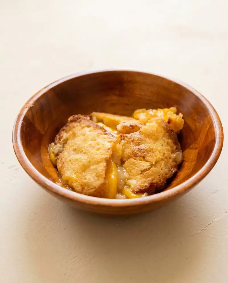 Golden Peach Cobbler Sheet Cake cooling in a metal baking pan with cinnamon swirl lines