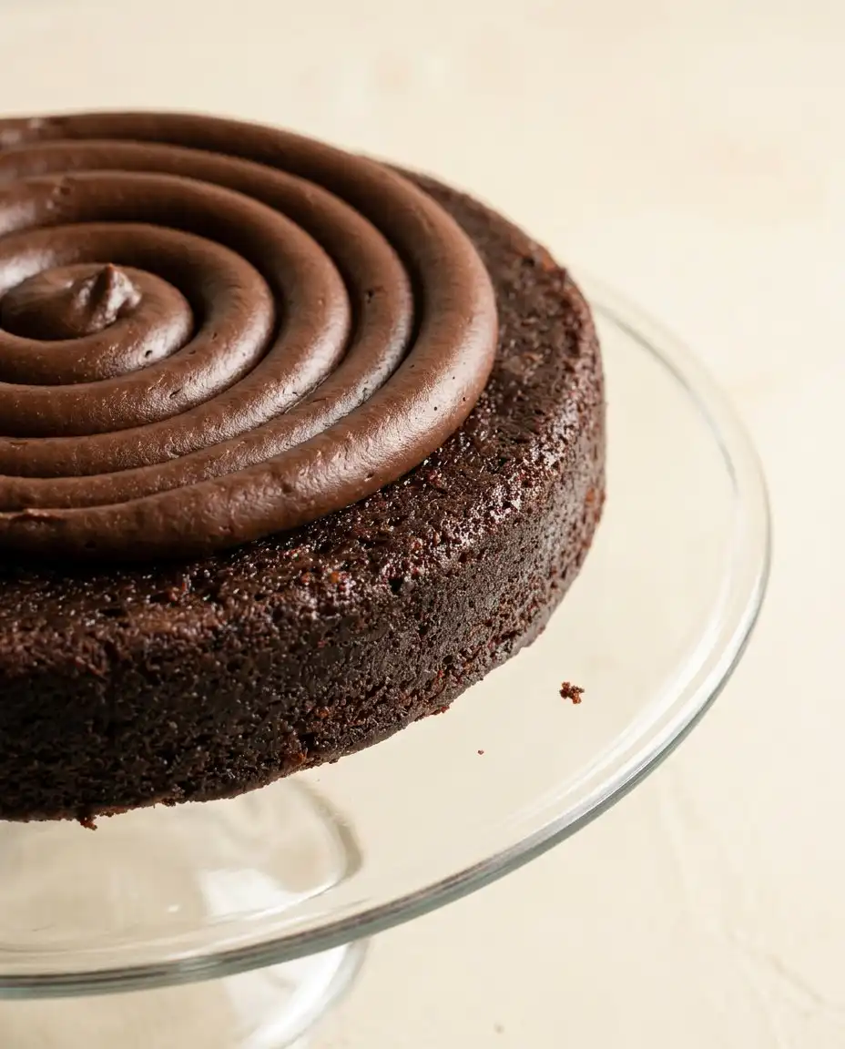 Pouring glossy chocolate syrup over a chilled Chocolate Mirror Glaze Cake to create a shiny reflective surface
