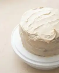An elegant slice of Pumpkin Spice Layer Cake with Cinnamon Cream Cheese Frosting displayed on a glass cake stand.