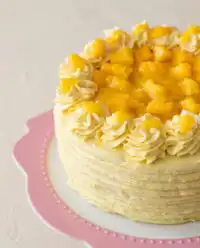 A stunning small-batch Mango Ombre Cake topped with fresh cubed mangoes on a wire cooling rack.