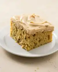 A close up of a sliced zucchini cake with cinnamon and nutmeg topped with cream cheese icing.