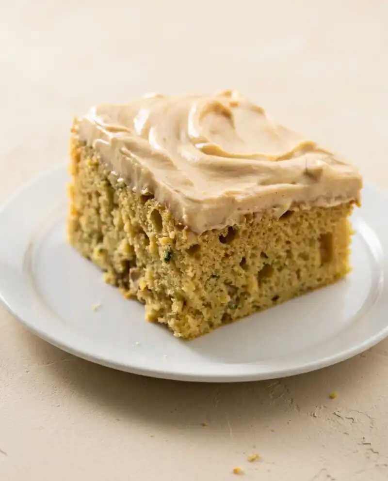 Home - Cake Half - Small Batch Baking & Cupcakes 7 A close up of a sliced zucchini cake with cinnamon and nutmeg topped with cream cheese icing.