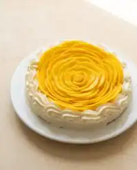 A beautiful Mango Flower Crown Cake decorated with golden mango slices on a vintage table.