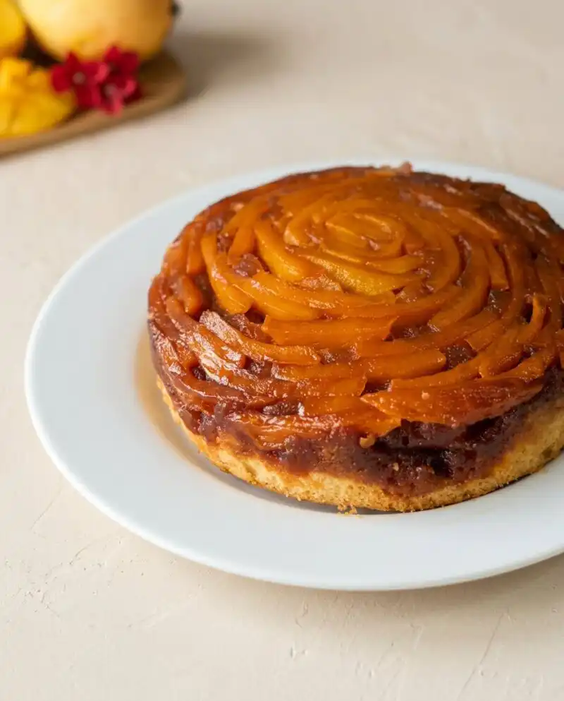 A warm slice of Mango Upside Down Cake sitting on a vintage plate in a sunny kitchen.