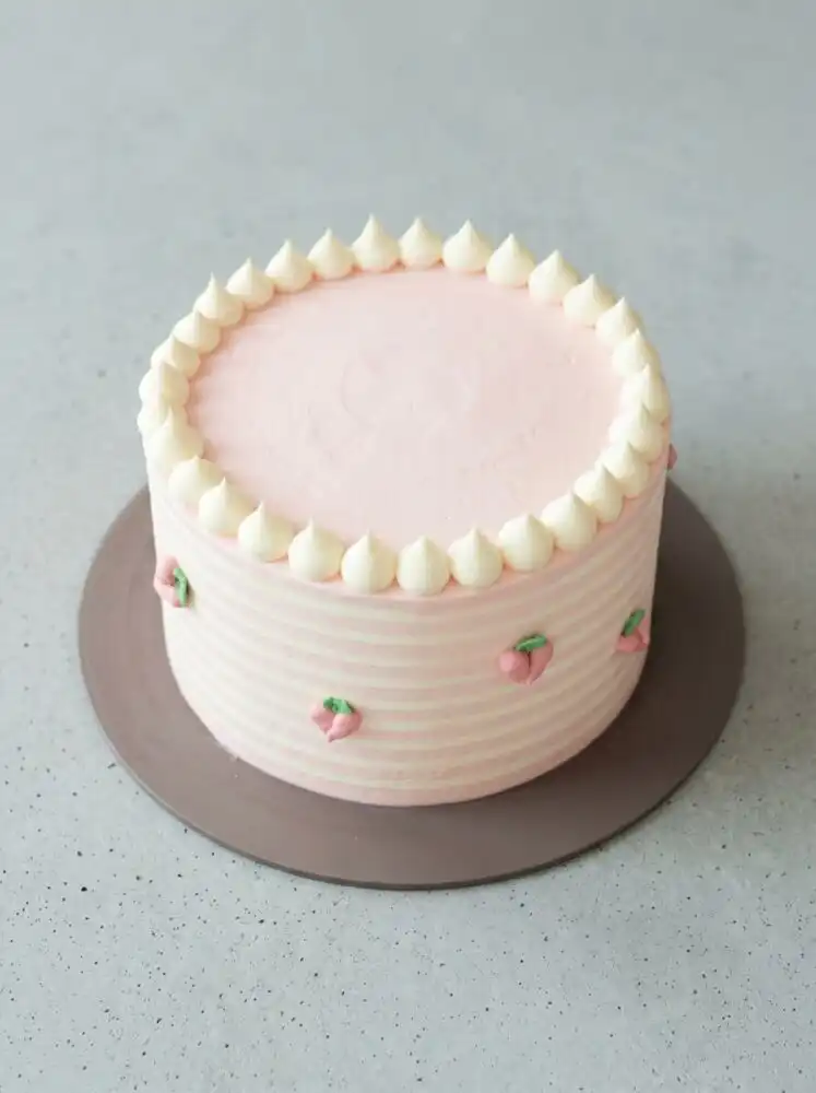 A gorgeous Peach Watercolor Cake Design resting on a vintage glass pedestal in a warm kitchen