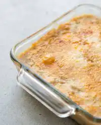 A baking dish filled with warm golden peach dump cake with frozen peaches straight out of the oven.