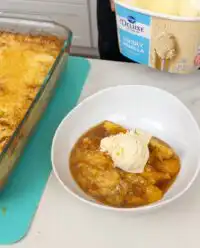 A warm Cinnamon Canned Peach Dump Cake fresh from the oven, served in a vintage baking dish.